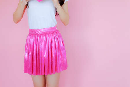beautiful asian female wearing white T-shirt and pink skirt on pink backgroundの写真素材