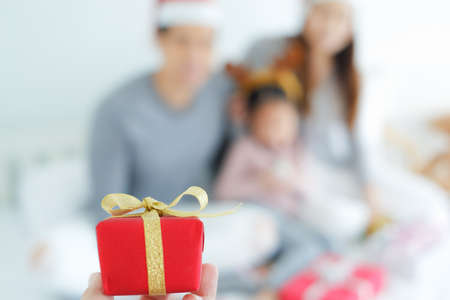 Close up red mini gift box with blur asian family celebration merry christmas and happy new year backgroundの写真素材