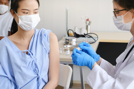 Caucasian doctor woman or nurse giving flu or antiviral vaccine to asian woman in hospital or clinic