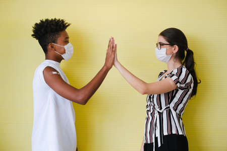 Portrait African-American man and caucasian woman wearing face mask and showing arm with bandage after getting flu or vaccineの写真素材