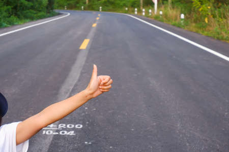 closeup thumb up of female on the road in the countryの写真素材