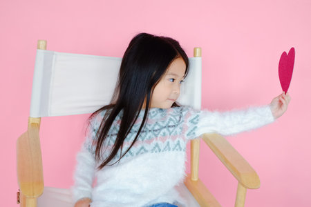 Portrait beautiful cute asian child girl on pink background with red heart sign, valentine day in love conceptの写真素材