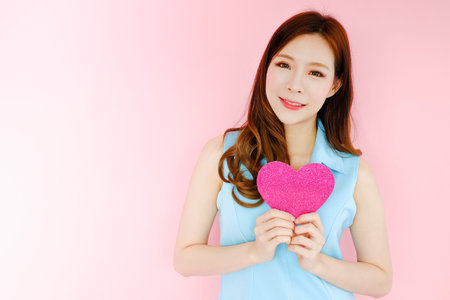 Portrait beautiful asian woman on pink background, valentine day in love concept, model holding red...