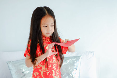 Portrait beautiful cute asian child girl wearing red mandarin gown or cheongsam dress on the bed...
