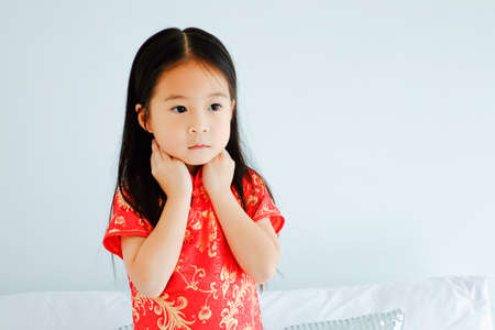 Portrait beautiful cute asian child girl wearing red mandarin gown or cheongsam dress on the bed, celebrate chinese new year conceptの写真素材