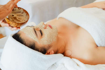asian woman having face treatment in spa salon on the bed, beauty natural facial maskの写真素材