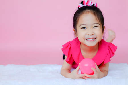 Little cute asia girl playing pink balls on pink backgroundの写真素材