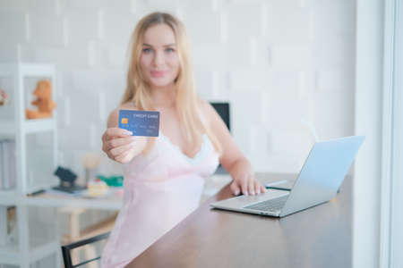 caucasian woman playing laptop with credit card in morningの写真素材
