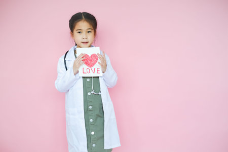 Portrait beautiful cute asian child girl on pink background with red heart sign wear Lab setの写真素材