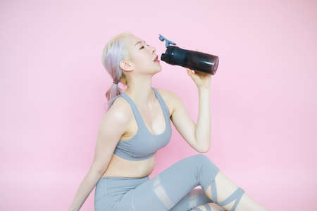 beautiful asian woman on pink background, fitness sports and recreation conceptの写真素材