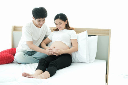 portrait asian young pregnant woman and husband happy together on the bed