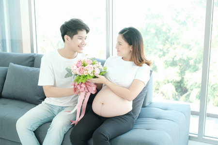portrait asian young pregnant woman and husband happy together on sofa