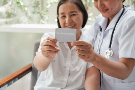 asian Female nurse and senior woman at hospital with health insurance cardの写真素材