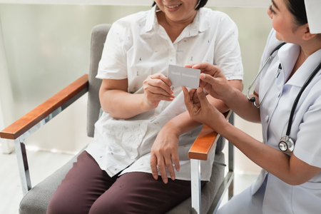 asian Female nurse and senior woman at hospital with health insurance card