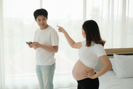 Unhappy angry asian pregnant woman because husband playing game online on smart phoneの写真素材