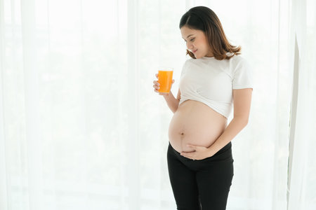 pregnant asian woman drinking orange juiceの写真素材