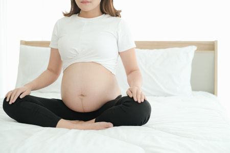 asian pregnant playing yoga poses on the bed
