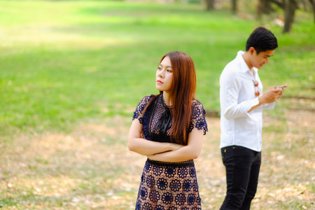Unhappy angry asian woman waiting to her boyfriend playing game online on smart phone, Couple in...