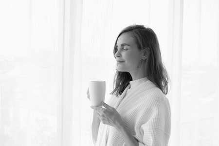 girl drinking hot coffee or tea in morning near window
