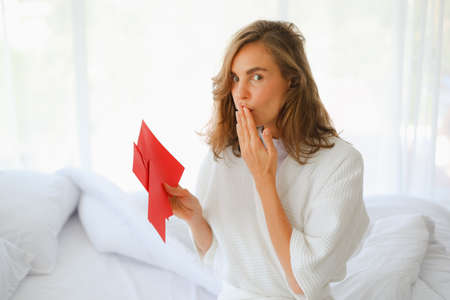 Caucasian woman receive bonus or or money with red envelope holding in hand is happily, chinese new year conceptの写真素材