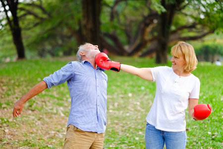 Portrait caucasian senior woman and old man, couple elderly fighting each other with boxing red...