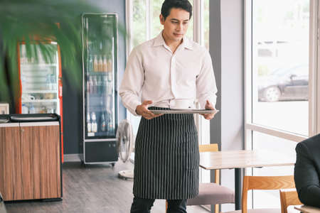 asian waiter served and serving coffee in cafe or restaurantの写真素材