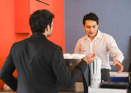 asian waiter serving caucasian businessman in cafe or restaurantの写真素材