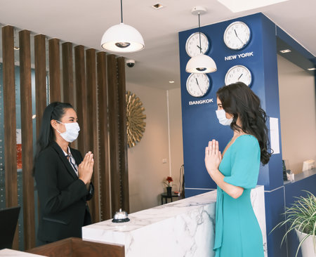 Asian girl receptionist and Caucasian woman traveler checking or checkout in hotelの写真素材