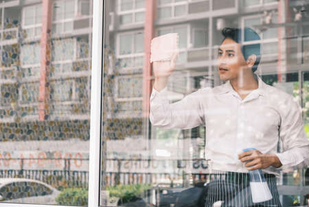 Asian man worker and cleaning glass windowの写真素材