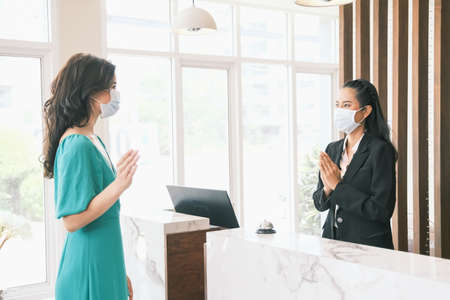 Asian girl receptionist and Caucasian woman traveler checking or checkout in hotelの写真素材
