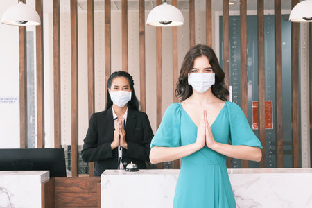 Asian girl receptionist and Caucasian woman traveler checking or checkout in hotelの写真素材