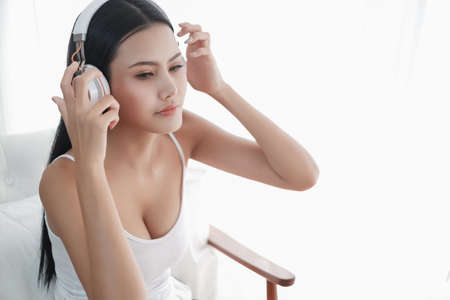 Asia woman sitting on the chair in morning with headphone and smart phoneの写真素材