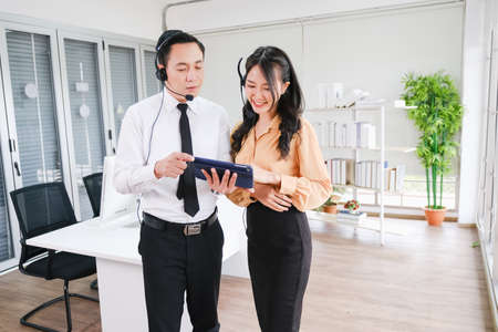 asian man and beautiful asian woman working call center operator with headset in office or workplaceの写真素材