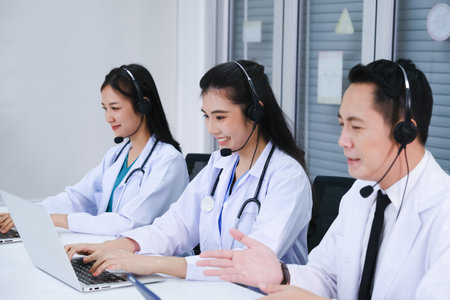 team asian doctor and nurse working call center operator with headset in hospital or workplaceの写真素材