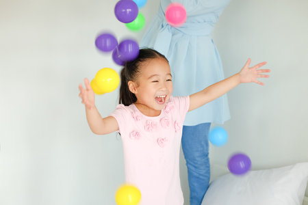 Asian family playing colorful ball on bedの写真素材
