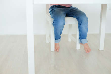 child's legs of asian child girl view under the tableの写真素材