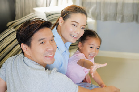 happy Asian family watching tablet on sofa in living room