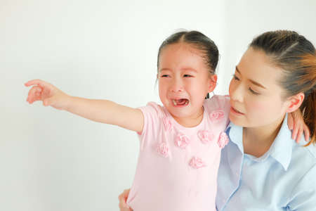 crying asian little girl being consoled by single momの写真素材