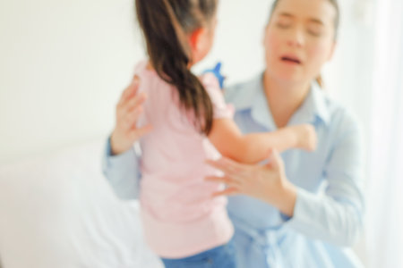 crying asian little girl being consoled by single momの写真素材