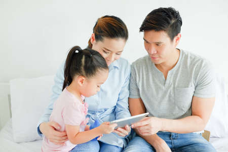 Asian family watching tablet in bed roomの写真素材