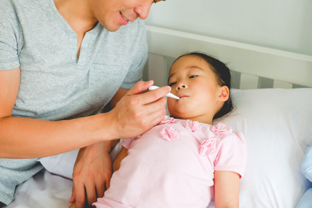 asian family tale care near small girl sick having high fever on the bedの写真素材