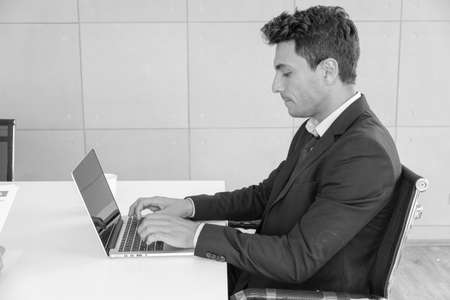 business caucasian man sitting in working with laptop in office near windowの写真素材