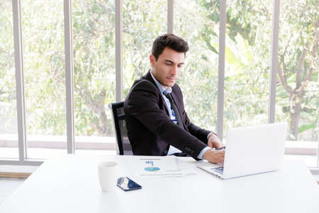 business caucasian man sitting in working with laptop in office near windowの写真素材