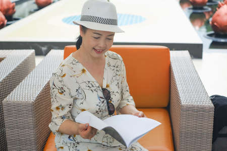 portrait senior asian woman wear a hat sit in lobbyの写真素材