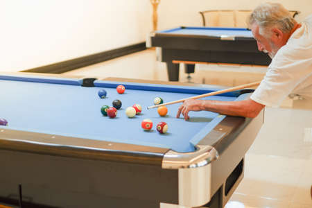 Portrait caucasian older, senior man playing billiards on pool table in sport clubの写真素材