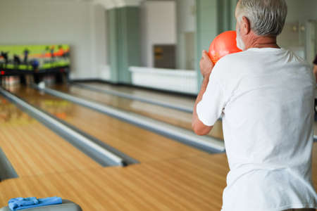 Rear view caucasian old man playing bowling in sport clubの写真素材
