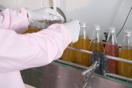 closeup in hand of female factory worker or woman expert quality staff is checking bottles line for beverageの写真素材