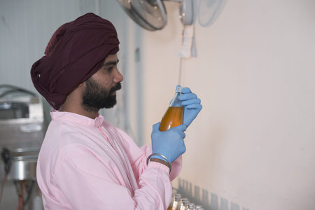 south Asia male factory worker or man expert quality staff is checking bottles line for beverage