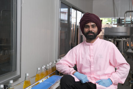 south Asia male factory worker or man expert quality staff is checking bottles line for beverage