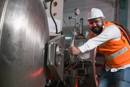 South asia male factory worker or Man engineer or expert staff wear safety vest and helmet of maintenance and checking steam boilerの写真素材